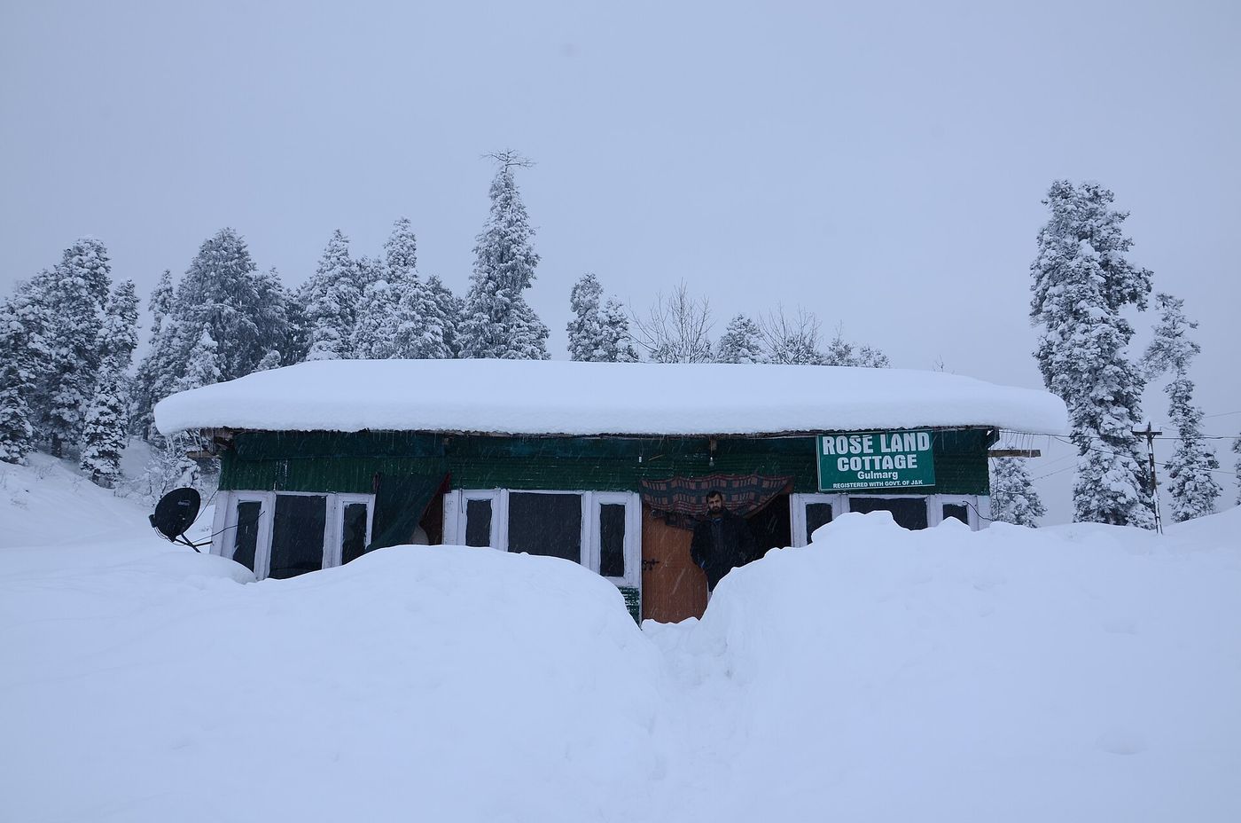 A wooden cottage buried in deep snow among pine trees in Gulmarg